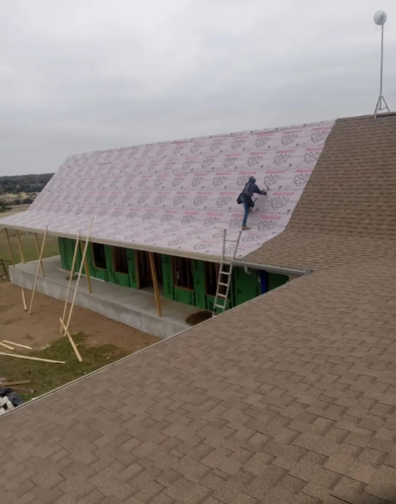 Worker preparing underlayment for a metal roof installation in Chicago